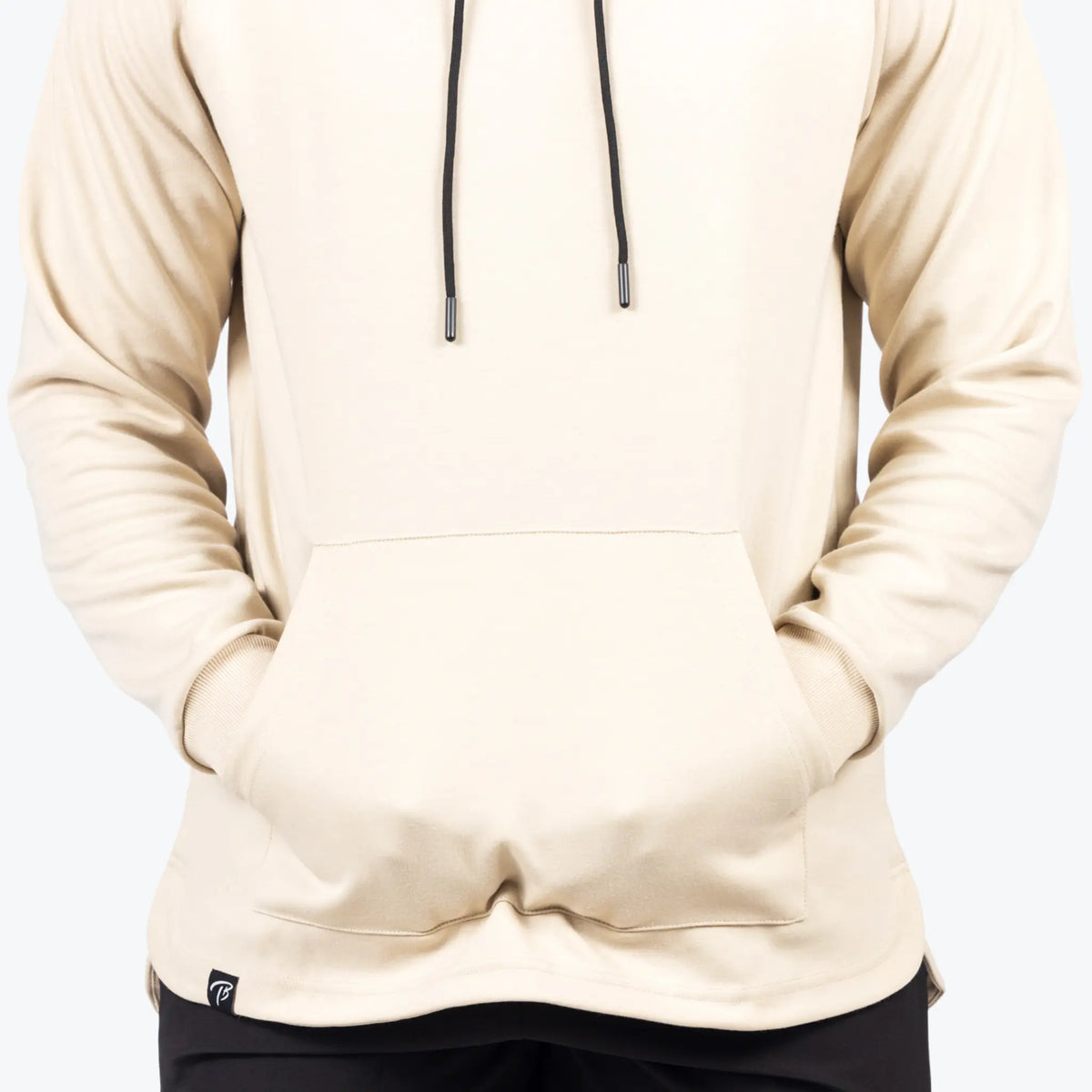 This image displays a close-up of a cream-colored training hoodie with a kangaroo pouch pocket. The design is sleek, featuring drawstrings with metal tips for an athletic look.
