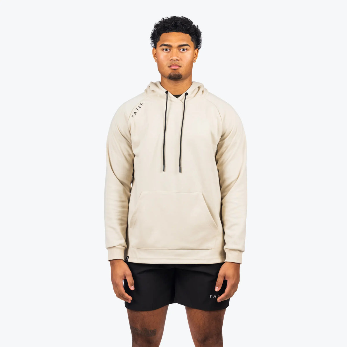 The uploaded image shows a model wearing a cream-colored professional baseball training hoodie with long sleeves, paired with black shorts, both adorned with the &quot;TATER&quot; logo. The hoodie, which is suitable for both sports training and casual wear, features a drawstring hood and a central front pocket. The style is modern and understated, emphasizing a practical and athletic lifestyle.