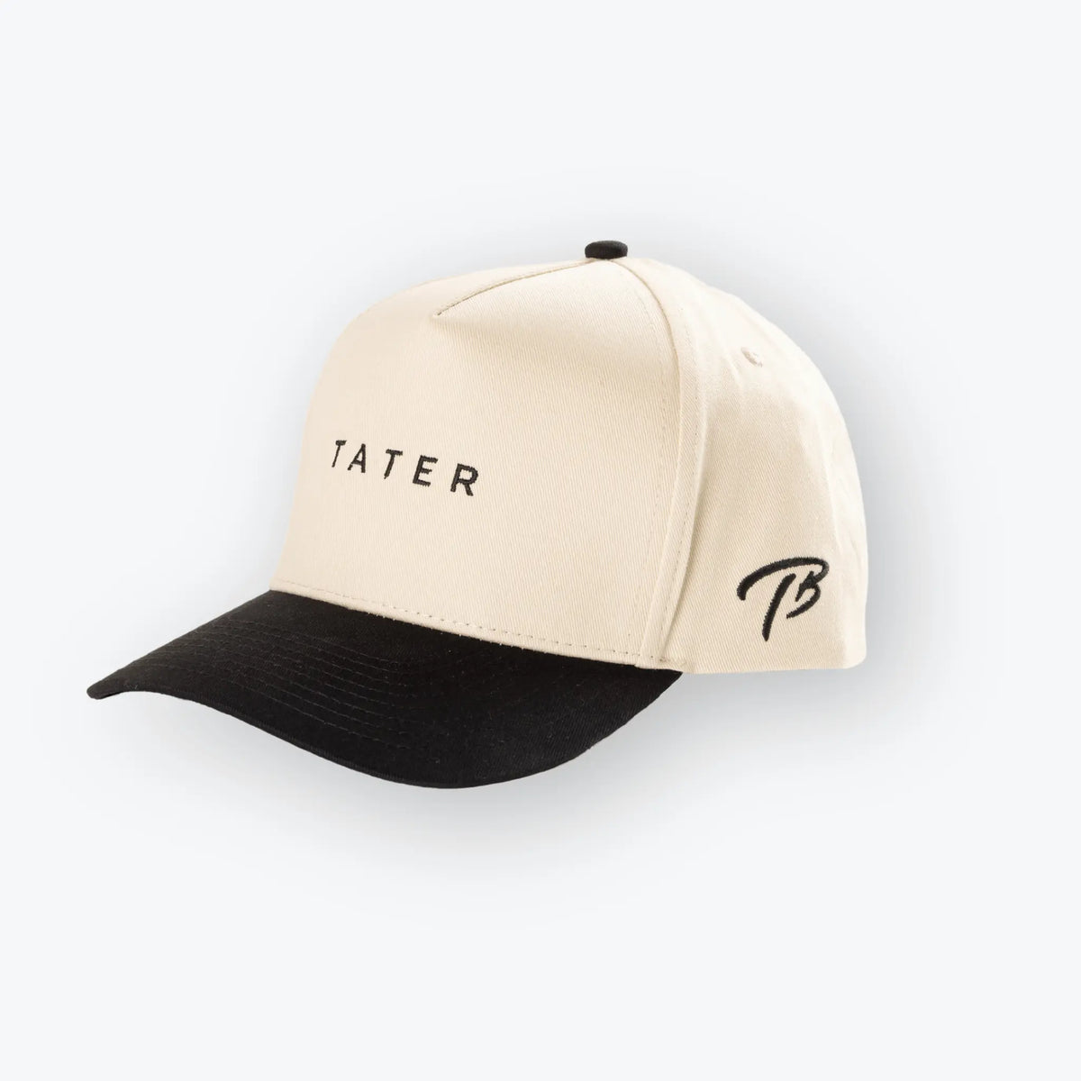 The image shows a tan and black snapback hat with the word &quot;TATER&quot; embroidered in black on the front. The Tater Baseball logo, a stylized &quot;TB,&quot; is also embroidered on the side of the hat in black. The cap&#39;s design is simple yet stylish, aligning with the aesthetics of contemporary baseball lifestyle apparel.