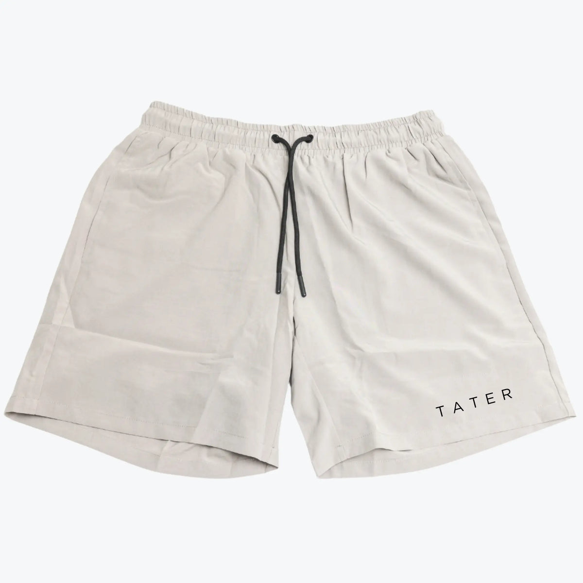 The image features a pair of light grey athletic shorts with a drawstring at the waist. On one leg, the word &quot;TATER&quot; is printed in black, which is the branding of the product. The shorts appear to be designed for physical activity, such as working out or sports practice, given the comfortable and breathable design. The color and minimal branding suggest a versatile piece of athletic wear that could be easily coordinated with other workout gear.